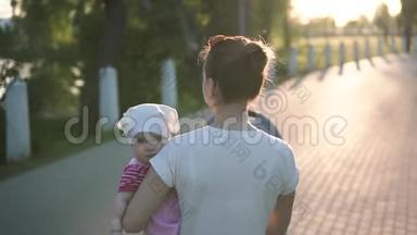 妈妈手牵着宝宝走在公园路上，慢镜头，阳光明媚